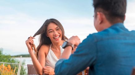 Smiling woman twirling her hair while on a date with a man.