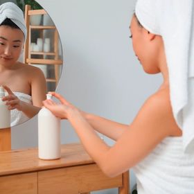Woman applying body lotion after showering.