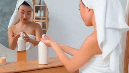 Woman applying body lotion after showering.