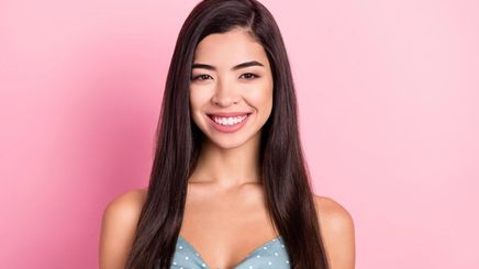 Young Asian woman with straight hair against pink background