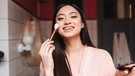 Asian woman doing her makeup
