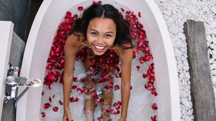Smiling Asian woman in a tub with rose petals