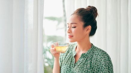 Smiling woman holding a cup of green tea.