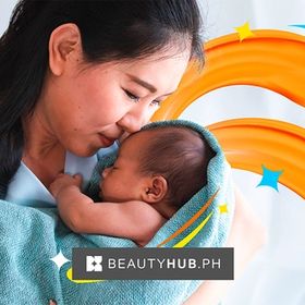 Asian mom cradling newborn baby in blue towel.