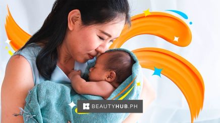 Asian mom cradling newborn baby in blue towel.