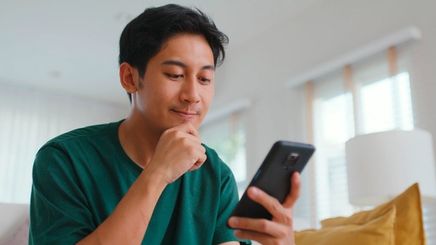 Asian guy in green shirt looking at his phone.