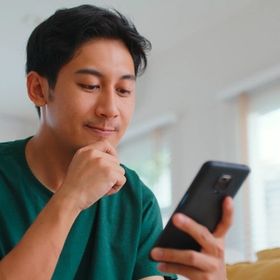 Asian guy in green shirt looking at his phone.