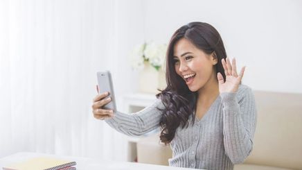 Asian woman waving at the screen during a video call 