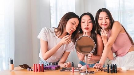 Three young Asian women playing with makeup.