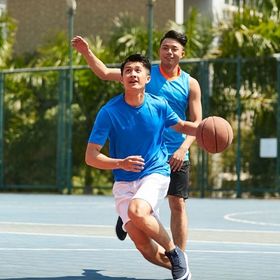 Two Asian men playing basketball outdoors