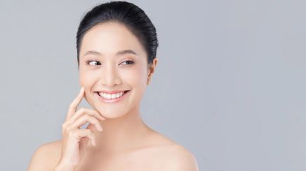 Asian woman with clear skin touching her face with finger. 