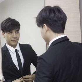 Asian man in suit looking at mirror 