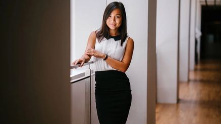 Fit Asian woman standing along a hallway.