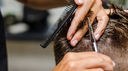 A barber styles a customer’s hair.