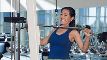 A strong Asian woman dusting chalk over a barbell