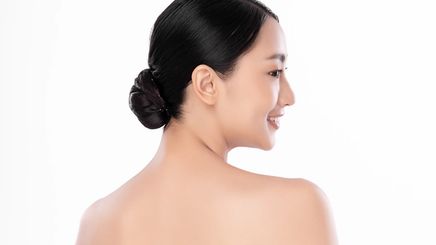 An Asian woman wearing a low bun and showing her upper back