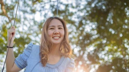 Asian woman with glowing skin smiling outdoors