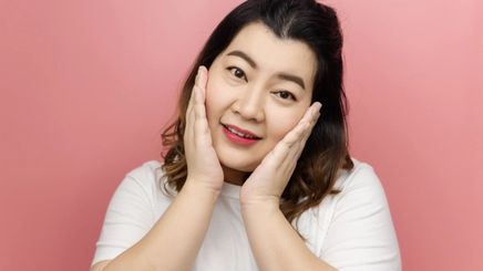 Asian woman smiling while touching face