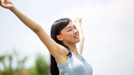 Woman throwing her arms up with a joyful expression.