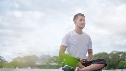 Asian man meditating outdoors