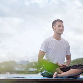 Asian man meditating outdoors