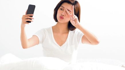 Woman taking a selfie in bed