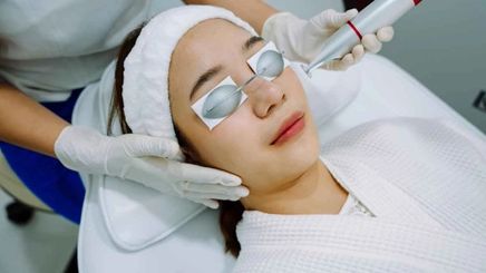 Woman getting a laser facial treatment at a clinic.