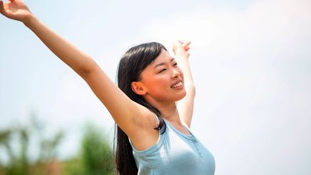 Woman throwing her arms up with a joyful expression.