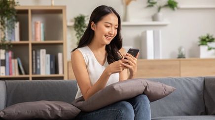 Asian woman looking at device, smiling