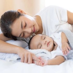 Asian woman fast asleep with her baby.