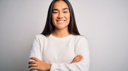 A smiling Asian woman in a white sweater