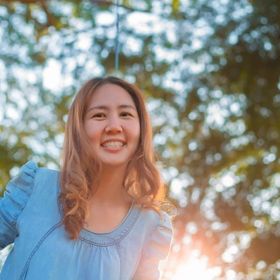 An Asian woman smiling happily outdoors.