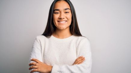 A smiling Asian woman in a white sweater