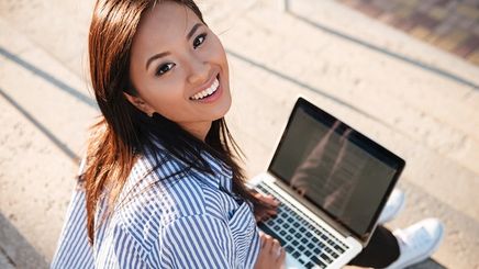 Beautiful Asian woman outdoors with laptop