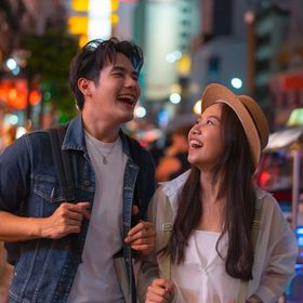 Asian man and woman laughing on the street.