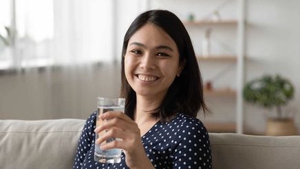 Smiling Asian woman holding a glass of water