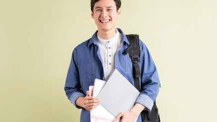 A well-groomed man smiling while carrying folders and a bag.