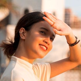 Smiling woman covering her face from the sun with her hand.