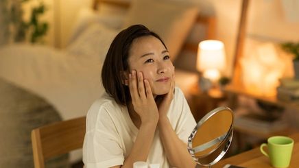 Smiling woman doing her nighttime skincare routine.
