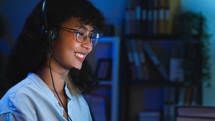 Asian woman wearing a headset while working at night.