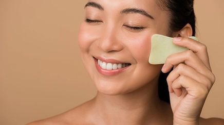 Woman massaging her face with a jade gua sha.