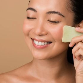 Woman massaging her face with a jade gua sha.