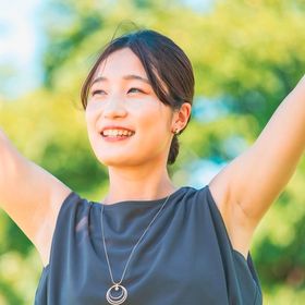 Asian woman with her arms raised outdoors.