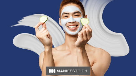 A smiling man holding cucumbers and wearing a face mask 