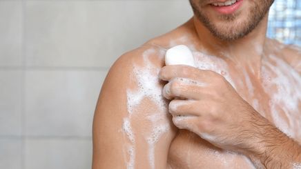 A man bathing holding soap in one hand