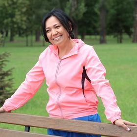 Asian woman in pink jacket leaning on bench