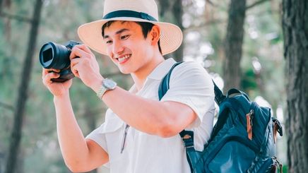 Young Asian traveler taking photos of the outdoors.