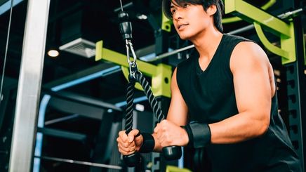 A portrait of man doing triceps pulldowns with a machine at the gym.