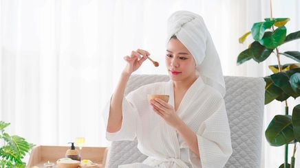 A portrait of woman in white bathrobe holding a bowl of honey and honey dipper