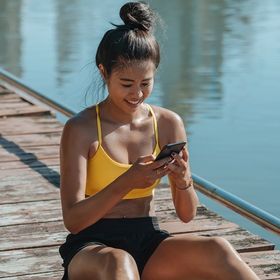 Sweaty Asian woman sitting on a wooden bridge with phone